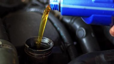 Tamir atölyesindeki araba motoruna yeni yağ döküldü..
