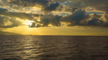 Orange Cloudy Sunset with Ocean and Cargo Ship on the Horizon Görüntüleri.