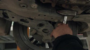 Mekanik denetim sırasında el aletleri ile kontrol edilirken süspansiyon ve şasi bileşenlerini gösteren bir araç şasisinin yakın görüntüsü. Otomotiv tamiri, bakım, mühendislik ve teknik görseller için ideal.