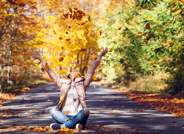 Young woman throwing leaves in the air — Stock Photo, Image