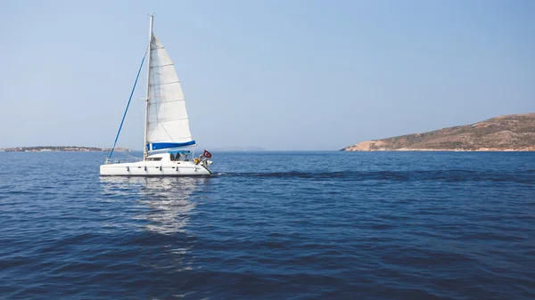 Segelbåt flyter på blå havet nära ön — Stockfoto