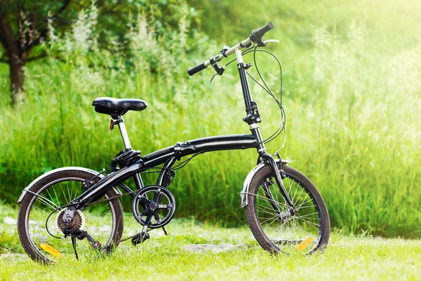 Черный складывающийся велосипед в траве — стоковое фото