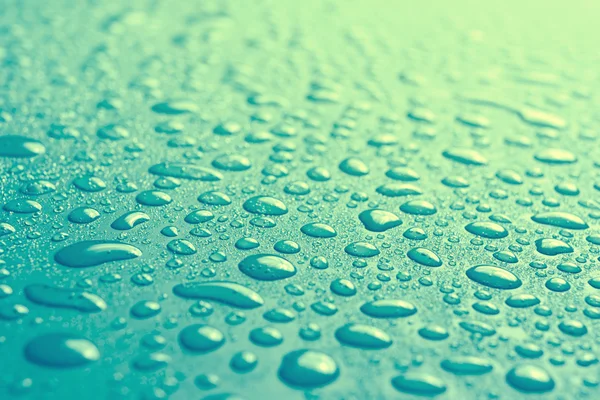 Gotas de agua en la superficie azul con poca profundidad de campo —  Fotos de Stock