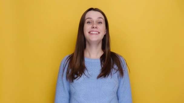一个兴奋而快乐的年轻黑发女人的画像 镜头对准自己 穿着蓝色针织毛衣 在黄色的工作室背景下被隔离 感情用事的生活方式 — 图库视频影像