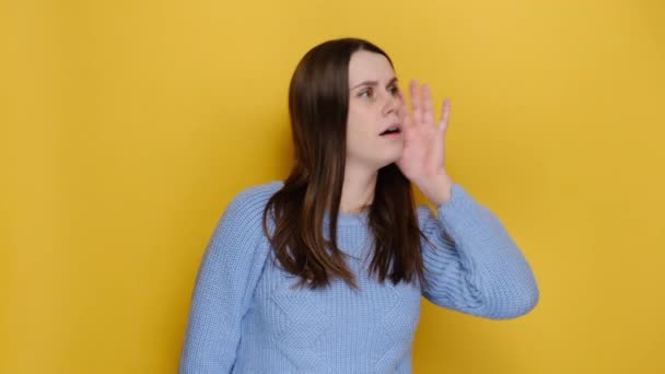 惊慌失措的年轻女子试著听到你偷听 专注地听着 抛开一切 穿着蓝色针织毛衣 孤立在黄色的背景音乐演播室里 感情用事的生活方式 — 图库视频影像