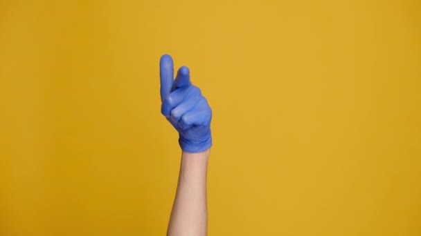 医療用保護手袋の男性の手を閉じてジェスチャーを作る黄色のスタジオの壁に隔離された近くに来てください ボディランゲージとCovid 19のコンセプト テキストや画像 プロモーションコンテンツの場所で — ストック動画