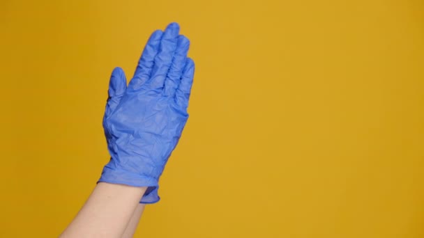 身着医用蓝色手套的无法辨认的女性紧紧地握住双手向上帝祈祷 为健康祈祷 被隔离在带有复制空间的黄色工作室墙上 宗教和验尸官概念 — 图库视频影像