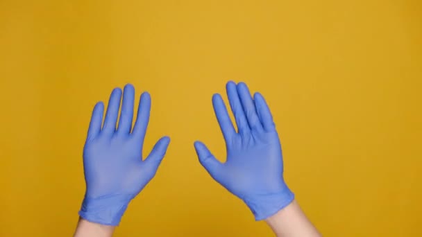 医療用保護手袋の男性の手のクローズアップは スタジオで黄色の背景に隔離された音楽リズムジェスチャーに彼女の指をスナップします 広告のスペースをコピーします テキストや画像の場所で — ストック動画