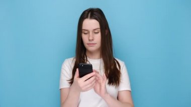 Şaşırmış sevimli kadın akıllı telefon cihazını işaret ediyor, grup sohbetinde sohbet etmeyi öneriyor, mavi duvarda izole edilmiş posta kutusu için tebrik mesajları almaktan memnun.