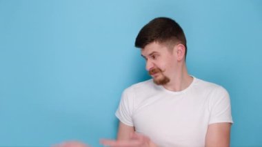 Kafası karışmış genç sakallı adamın portresi fotokopi odasını gösteriyor, hayır teşekkürler, beyaz tişört giymiş, mavi arka plan stüdyosunda izole edilmiş. Duyguların insanları yaşam tarzı konsepti