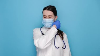 Profesyonel kadın doktor lateks koruyucu eldivenlerle maske takıyor, beyaz üniforma giyiyor ve steteskop kullanıyor, mavi arka planda izole edilmiş. Covid 19, sağlık çalışanları ve virüs konseptini önleme