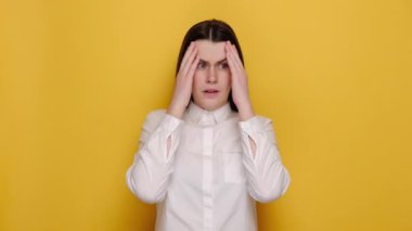 Hasta 20 'li yaşlarda genç bir kadının portresi baş ağrısı çeken baş masajı yapan tapınaklara dokundu. Kötü hissetti, beyaz gömlek giydi, sarı stüdyo arka planında izole edildi..