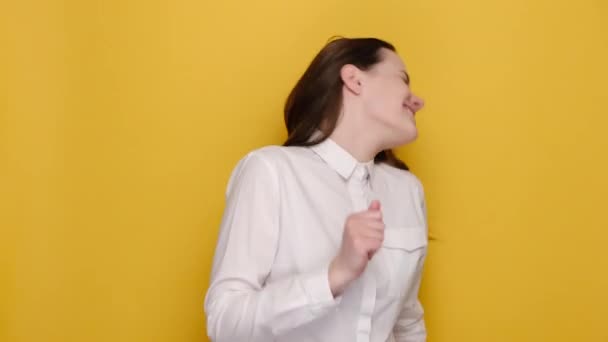 快乐有趣的年轻商界女性20多岁的舞蹈表现出胜利的标志握紧拳头 身穿白衬衫 在黄色的工作室背景下显得孤立无援 人的情感概念 — 图库视频影像