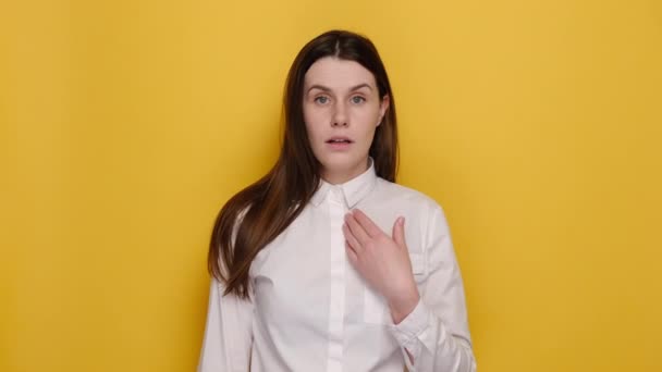 不満な若いブルネットの女性が指を指している自分自身は私に感謝しないでくださいと言う私はそれを必要としない 白いシャツを着て 黄色のスタジオの背景に隔離されたポーズ 人々の感情の概念 — ストック動画