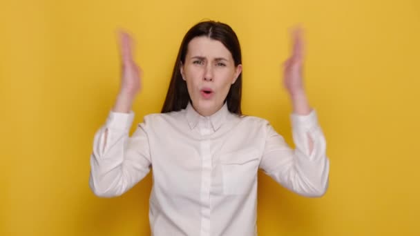怒り狂った若いビジネス女性の肖像は 白いシャツを着て 黄色のスタジオの背景に隔離されたポーズを身に着けて叫んで手を広げている 人々の感情ライフスタイルのコンセプト — ストック動画