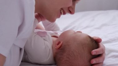 Neşeli anne ve tatlı bebek sıcak yatakta uzanmış buruna dokunup öpüyor. Sevecen, şefkatli bir anne küçük bir kıza sarılıyor sevgi ve şefkat hissediyor. Bebek konseptiyle annelik gününüz kutlu olsun.