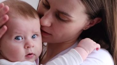 Sevecen, genç bir anneyi kucağına alıp küçük bir çocuğu öpen sevimli bir kızı kucaklamak. Mutlu şefkatli anne evde duran küçük kızına sarılıyor. Seçici odak