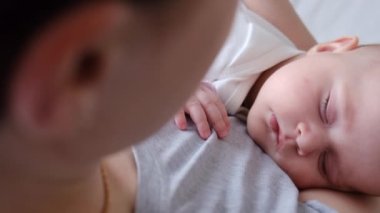 Nazik ve şefkatli genç bir annenin kucağında uyuyan güzel bir kız çocuğu, parlak bir çocuk odasında durup güzel anların tadını çıkarması. Ebeveynlik ve aile sevgisi kavramı