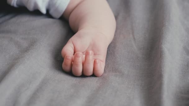 在舒适的灰色床上 用五只手指头紧紧地抱着幼小的幼儿小手 婴儿护肤概念 — 图库视频影像