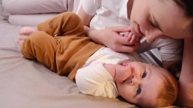 Neşeli, şefkatli, güzel anne vuruşları ve yatak odasında rahat bir yatakta uzanan küçük kızı öpmesi ebeveynlerin ve çocukların birbirlerine bağlandığı tatlı anların tadını çıkarması. Bağ, aile ve gelincik kavramı