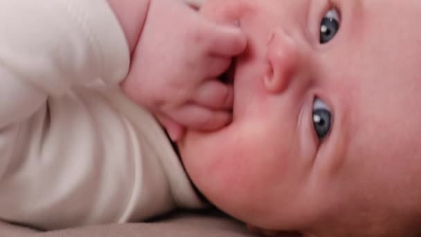 有选择性地集中拍摄可爱的女婴的肖像 她把拳头放在舒适的床上 躺在家里 看着相机 漂亮的新生婴儿在卧室里玩耍 儿童保育概念 — 图库视频影像