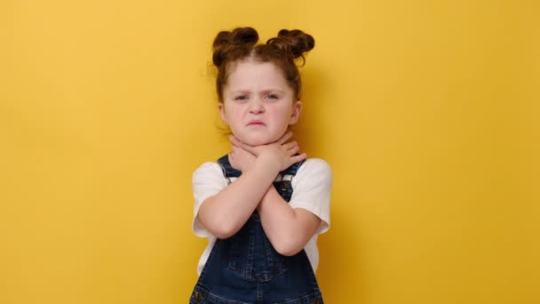 不健康な女の子の子供のタッチ首を飲み込むのは難しい痛みを感じる不快感 喉の痛み刺激や声の損失 黄色のスタジオの背景に隔離された 扁桃炎狭心症の概念 — ストック動画