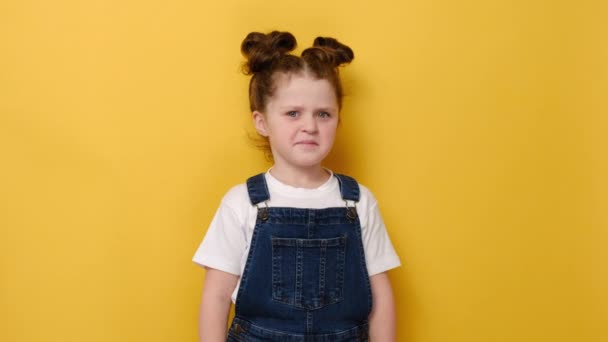 描述不快乐的学龄前小女孩心情不好 不喜欢嗅觉和鼻子闻起来怪怪的气味 穿着白色的T恤 在黄色的工作室背景下被隔离 六岁的孩子看着相机 — 图库视频影像