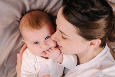 Sevgi dolu genç annenin yakın portresi. Sevimli küçük bebeği kucakla. Sevecen küçük bebeği kucakla, neşeli anneyi oyna.
