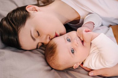 Beyaz tenli, genç bir anneyi sevmek, tatlı bir kızı kucaklamak, rahat bir yatakta yatmak. Gülümseyen bir anne ve el ele tutuşan küçük şirin bir çocuk. Anne ve çocuğun hassas anları. Seçici odak