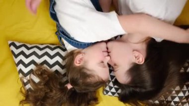 Üst tabaka mutlu, sevimli, sevgi dolu küçük bir kız çocuğu sevgi dolu, sevgi dolu, genç bir anneye sarılmış, gözleri kapalı, çadırda uzanmış, sevimli, küçük bir kız çocuğu annesine sarılıyor, şefkatli, tatlı bir anın tadını çıkarıyor.