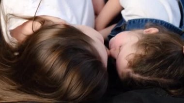 Mutlu anne ve küçük kızın birbirine bağlanıp burunlarına dokunarak güldüğü, rahat bir yatakta uzandığı, şefkatli bir annenin tatlı küçük çocukla eğlendiği seçici bir odak noktası.