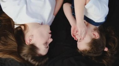 Şakacı genç anne ve komik küçük kızın yatakta uzanıp suratlarını buruşturarak parmaklarıyla eğlenirken sahte gözlüklerle kameraya mutlu bakışlarının üst görüntüsü. Aptallar Günü