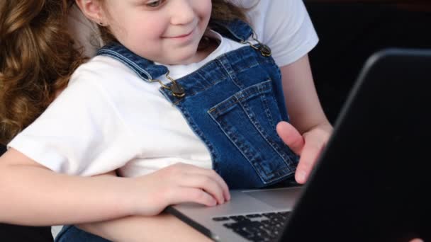 笑顔若いお母さんとかわいい子供の娘が楽しいショッピングオンライン座っている居心地の良いベッド 幸せなお母さん教える小さな子供の女の子は ラップトップアプリケーションを使用して 漫画を見たり コンピュータ上でビデオ通話を行う — ストック動画