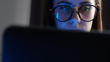 Gözlüklerini çıkaran genç üzgün kadın bilgisayarın dizüstü bilgisayarla aynı yatakta oturmasından yorulmuş, yorgun kızın görme sorunu var. Uzun dizüstü bilgisayar kullandıktan sonra kuru gözlere masaj yapıyor.