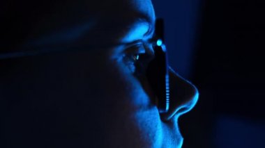 Dizüstü bilgisayarda çalışan genç bir kadının seçici odak noktası. Gözlüklü, yansımalı, neon mavi ışıkta bilgisayar kullanan serbest çalışan bir kızın yan görüntüsünü kapatın. Geceleri not defteri olan serbest çalışan bir kadın.