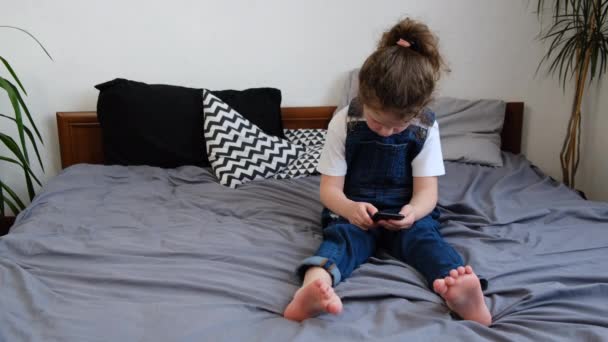 Linda Niña Preescolar Sentada Cama Acogedor Dormitorio Con Teléfono Inteligente — Vídeo de stock