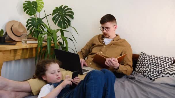 Pai Com Filhinha Sentada Cama Casa Usando Laptops Telefone Consumidores — Vídeo de Stock