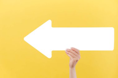 Güzel bir kadının elinde, büyük beyaz bir okla, reklam için fotokopi odası olan sarı arka plan duvarının üzerinde izole edilmiş bir şekilde. Reklam alanı, model