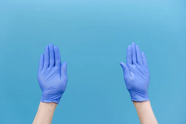 Close up of male hands in medical protective latex gloves snaps her fingers to music rhythm gesture, isolated over blue studio background. Copy space for advertisement. With place for text or image
