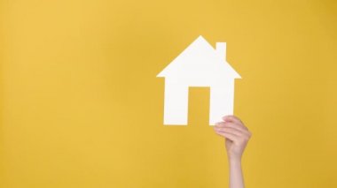 Beyaz Saray 'ın kağıt modelini tutan kadınların ellerini kapat ve iyi bir jest yap. Reklam için fotokopi alanı olan sarı arka plan duvarına izole edilmiş. Kabullenme tamam ve ipotek kavramı