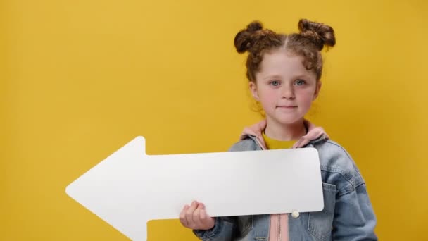 広告のためのコピースペースと黄色のスタジオの背景に隔離されたデニムジャケットに身を包んだジェスチャーのような親指のアップで脇に示すかわいい就学前の女の子 人々の感情の概念 — ストック動画