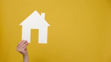 Küçük beyaz kağıt ev ve megafona, ev kredisi açık artırmasına ev kirası mülkiyet bilgilerine, sarı stüdyo arka planında izole edilmiş kadınlara yakın durun. Emlak pazarlama ve ipotek kavramı