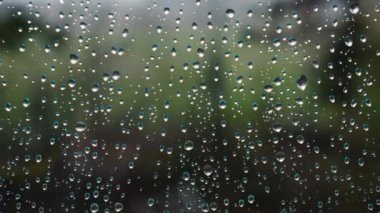 Yağmur damlalarının seçici odak noktasını kapat ve arka planda yeşil ağaç olsun. Dairenin içinden üzücü yağmurlu bir gün. Hygge ve değişken hava durumu kavramı