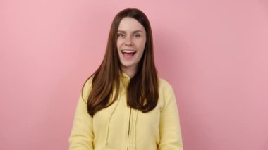 Oyuncu genç kadın büyük beyaz hashtag sembolü ve gülümseme arkasına saklanır, reklam blogu, internet trendlerini takip etmek için esrar işareti, sarı kapüşonlu giyinir, stüdyoda pembe renkli arka plan üzerine izole edilmiş