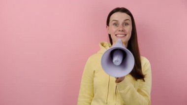 Heyecanlı genç esmer kadın megafonla bağırıyor işaret parmağı yukarı doğru, sarı kapüşonlu giyiyor, pembe arka planda fotokopi alanı ile izole edilmiş poz veriyor. İnsanlar duygusal yaşam tarzı konsepti
