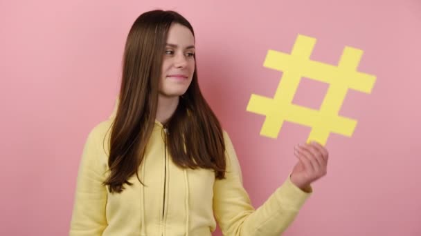 Jovem Sorrindo Brincalhão Segurando Sinal Hashtag Amarelo Mostrando Gesto Conteúdo — Vídeo de Stock