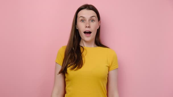 魅力的な幸せなブルネットの女性は大きな黄色のハッシュタグと小さな赤いハートシンボルを持っており カメラを見て笑って ピンクのスタジオの背景に隔離されたポーズでパーカーを身に着けています ソーシャルメディア ブログコンテンツ — ストック動画