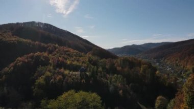 Sonbahar güneşli bir günde dağların üzerinden kırsal alana uçuşun insansız hava aracı görüntüsü. Arka planda sıradağlar var. Gezgin şehvet, büyüleyici ve ürkütücü doğa. Temiz ve huzurlu bir manzara