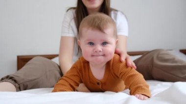Mutlu, sevimli, sevimli, sevimli, evlat edinilmiş, beyaz, beyaz bir kızın portresi. Sevgi dolu, genç bir annenin yanında, rahat beyaz bir yatakta yatıyor. Çocuk bakımı, annelik ve çocuk konsepti. Seçici odak