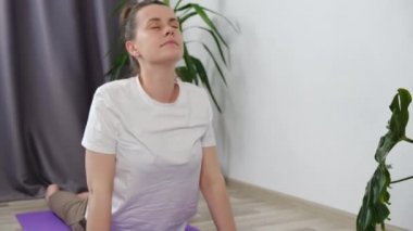 Çevrimiçi egzersiz konsepti. Yoga yapan genç bir kadın, yoga yapan bir kız, yoga dersi alan bir kız, dizüstü bilgisayarla evde paspasa uzanan bir beden esnekliği eğitimi veren bir kız.